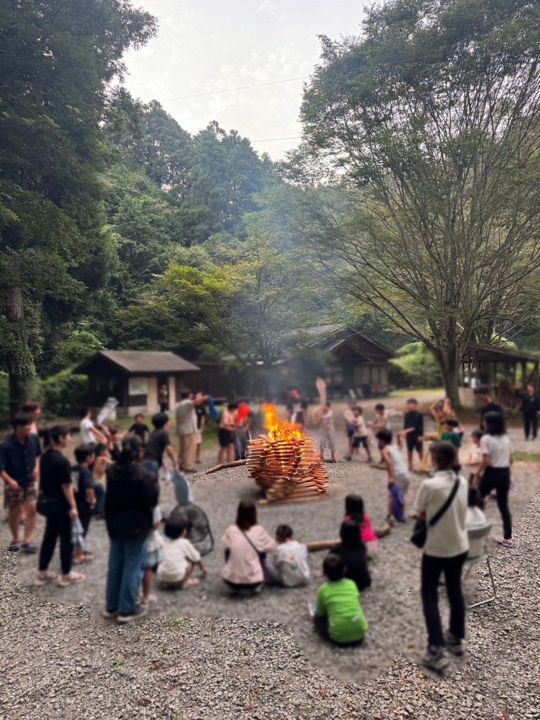 自然の中でキャンプファイヤーを囲む子どもたちと参加者